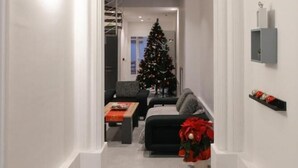 Un couloir décoré d’un sapin de Noël, avec un canapé et une table basse.
