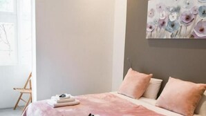 Une chambre à coucher moderne avec un grand lit, un tableau accroché au mur et une chaise dans un coin.