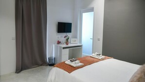 A hotel room with a bed, a desk with a flat-screen TV, a mirror, and a door. - Wonderful Double Room in Malta - Bb Marina (Pieta)
