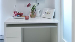 A white desk with a flat-screen TV, a vase with flowers, a framed picture, a kettle, and a glass of juice. - Wonderful Double Room in Malta - Bb Marina (Pieta)