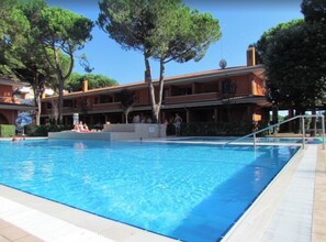 A swimming pool with a clear blue water surface, surrounded by a tiled deck. - Flat in a Poolside Residence-beahost (San Michele al Tagliamento)