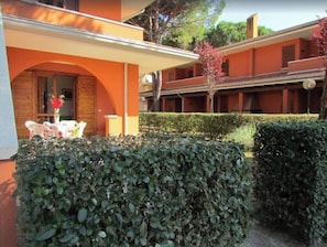 A building with an arched entrance, a covered patio area, and a neatly trimmed hedge. - Flat in a Poolside Residence-beahost (San Michele al Tagliamento)