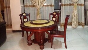 Un comedor con una mesa redonda y cuatro sillas, un ventanal con cortinas y un suelo de baldosas.