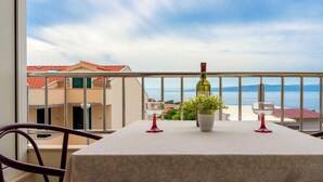 Un balcone con un tavolo, due bicchieri di vino rosso, una bottiglia di vino e una pianta in vaso.