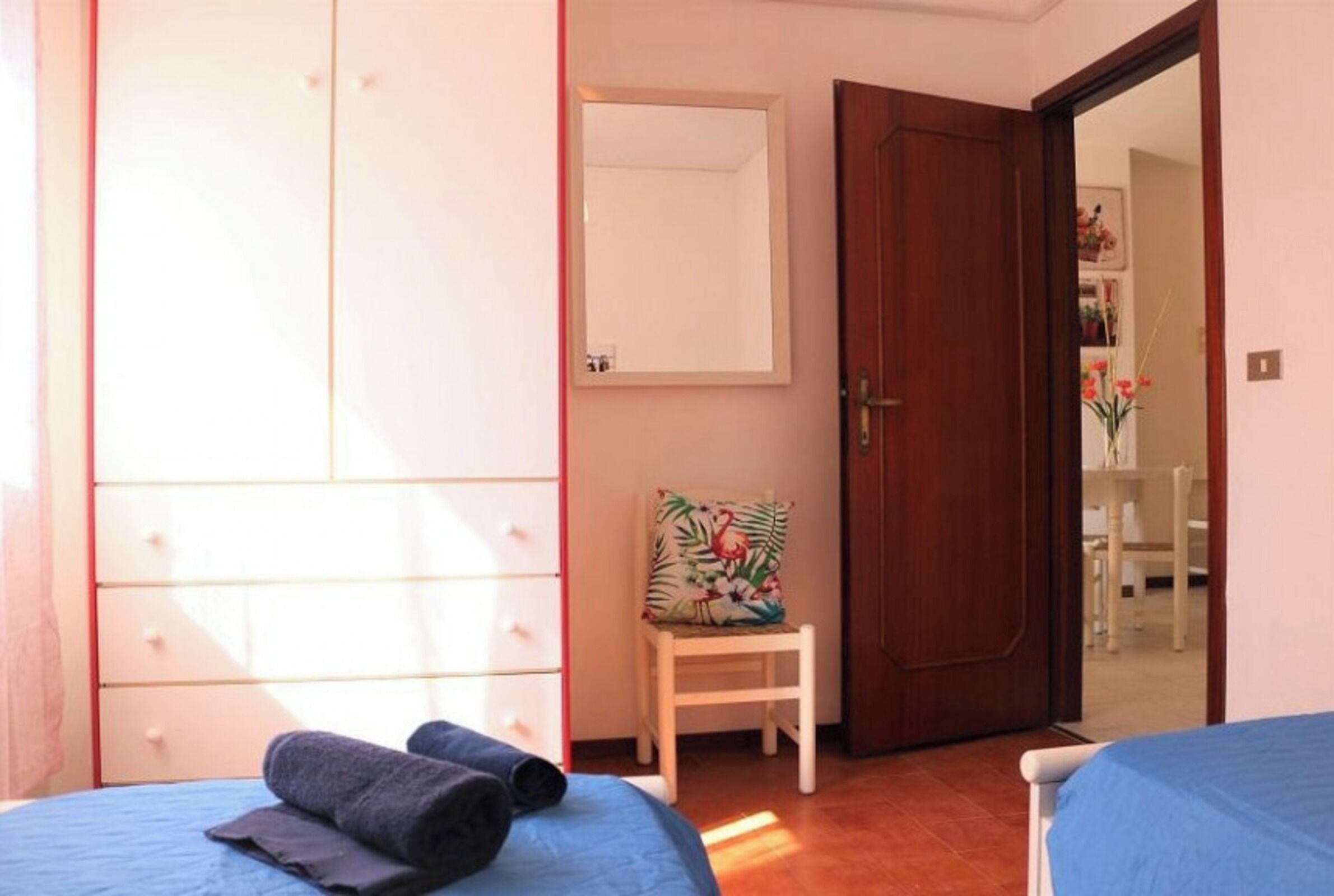Camera da letto con due letti, un armadio, una sedia e una porta che dà su un'altra stanza.