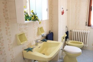 Une salle de bain avec un lavabo jaune, des toilettes et un bidet.