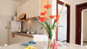 A modern kitchen with white cabinets, a built-in oven, and a countertop with a vase of flowers and starfish decorations. - Cosy Flat 80mt From the sea (San Michele al Tagliamento)