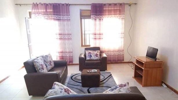 A living room with two sofas, a coffee table, and a TV stand. - Nice Fully Furnished Apartment in Kampala (Kampala)