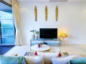 A modern living room with a flat-screen TV, a glass coffee table, and a sofa with patterned cushions. - Beautiful 1br Plunge Pool Villa Walk To Bangtao Beach (Choeng Thale)