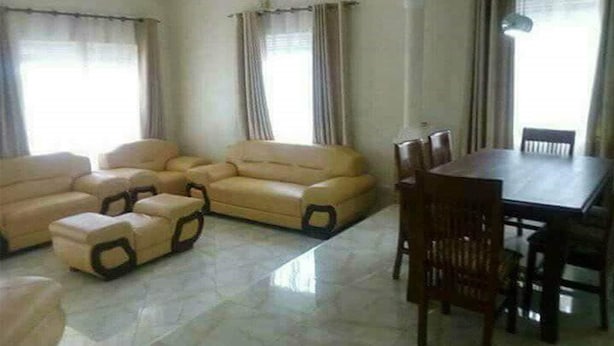 A living room with a beige sofa set, a dining table with chairs, and large windows with curtains. - Wonderful Apartment in Kampala (Kampala)