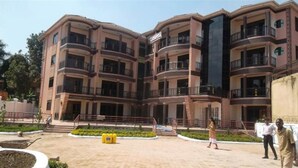 A multi-story building with balconies, a central courtyard, and a landscaped garden area. - A Wonderful Apartment Wail in the Incredible City of Kampala (Kampala)