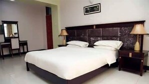 A standard hotel room with a large bed, two bedside tables with lamps, a mirror, and a framed picture on the wall. - Apartment in the City of Kampala (Kampala)