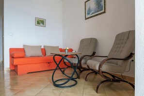 Un salon avec un canapé, deux fauteuils, une petite table et un tableau accroché au mur.