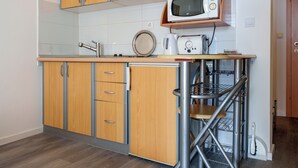 Cozinha com armários de madeira, micro-ondas, torradeira e pia.