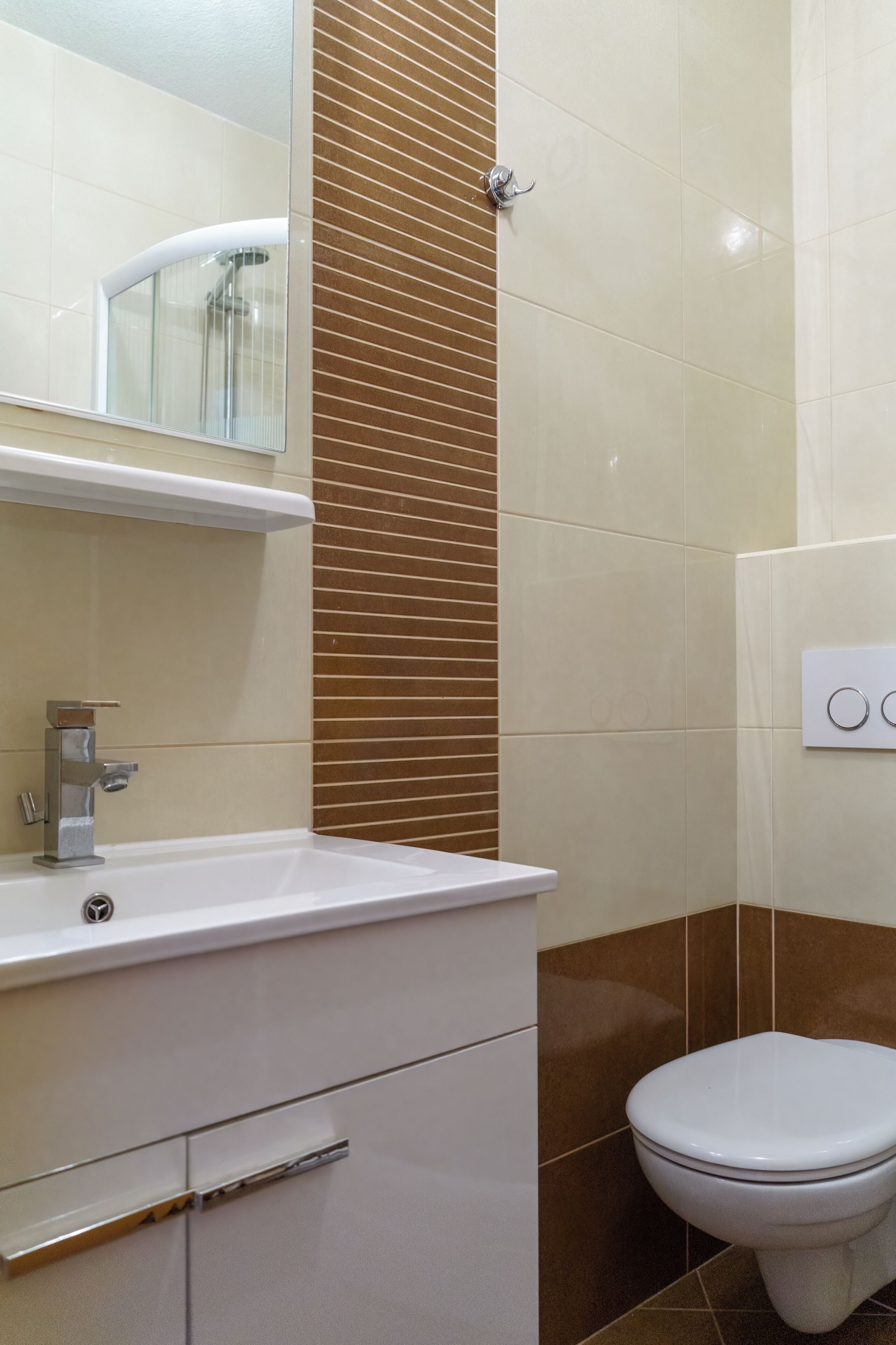 A bathroom with a white sink, a mirror, a toilet, and a wall-mounted light switch.
