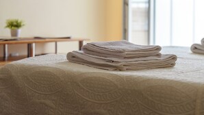 Um conjunto de toalhas dobradas em uma cama com um cobertor texturizado.