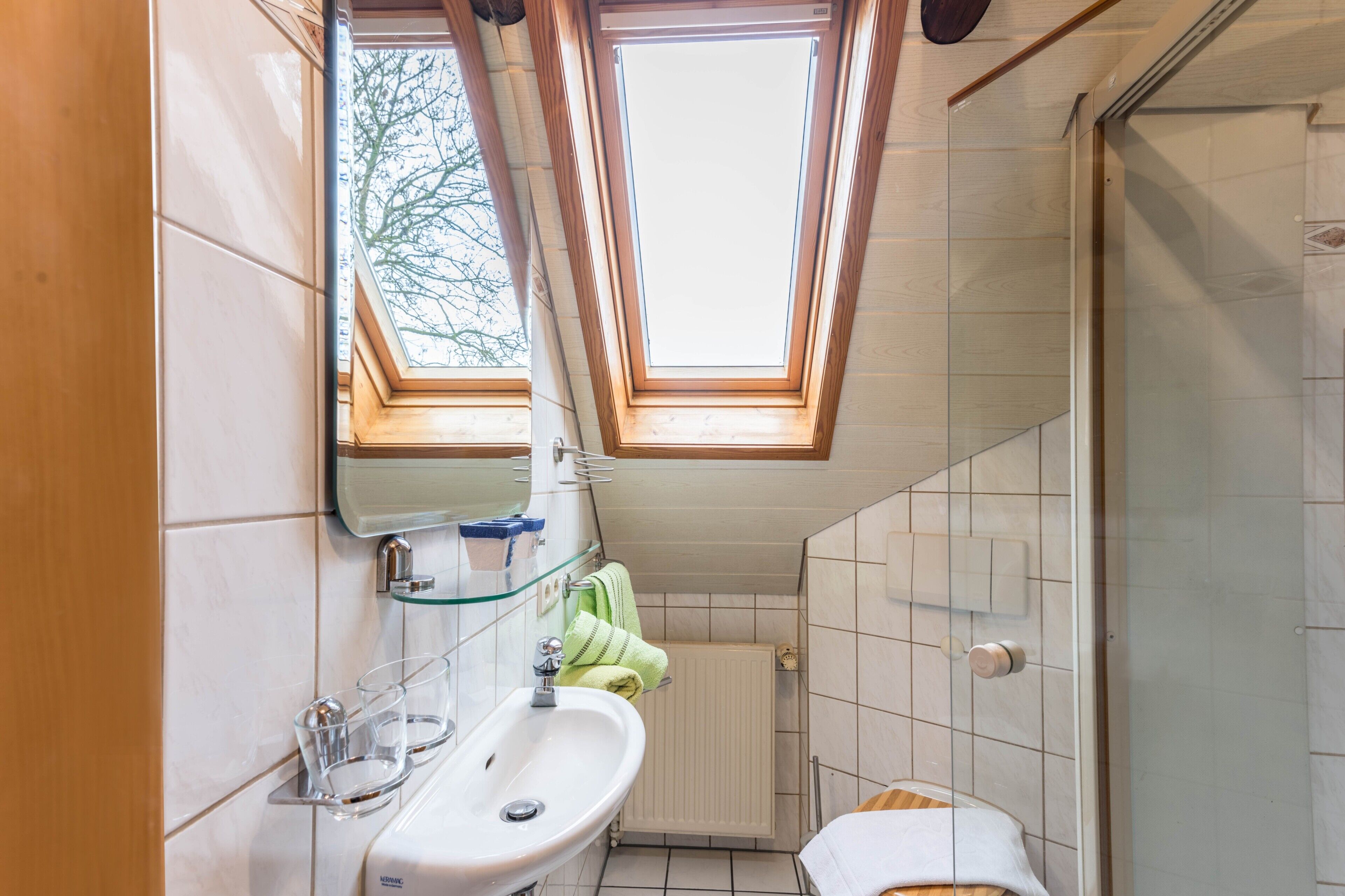 A bathroom with a skylight, a sink, a mirror, and a toilet.