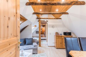 Una habitación acogedora con techo de madera, un sofá, una mesa de comedor y una zona de cocina.