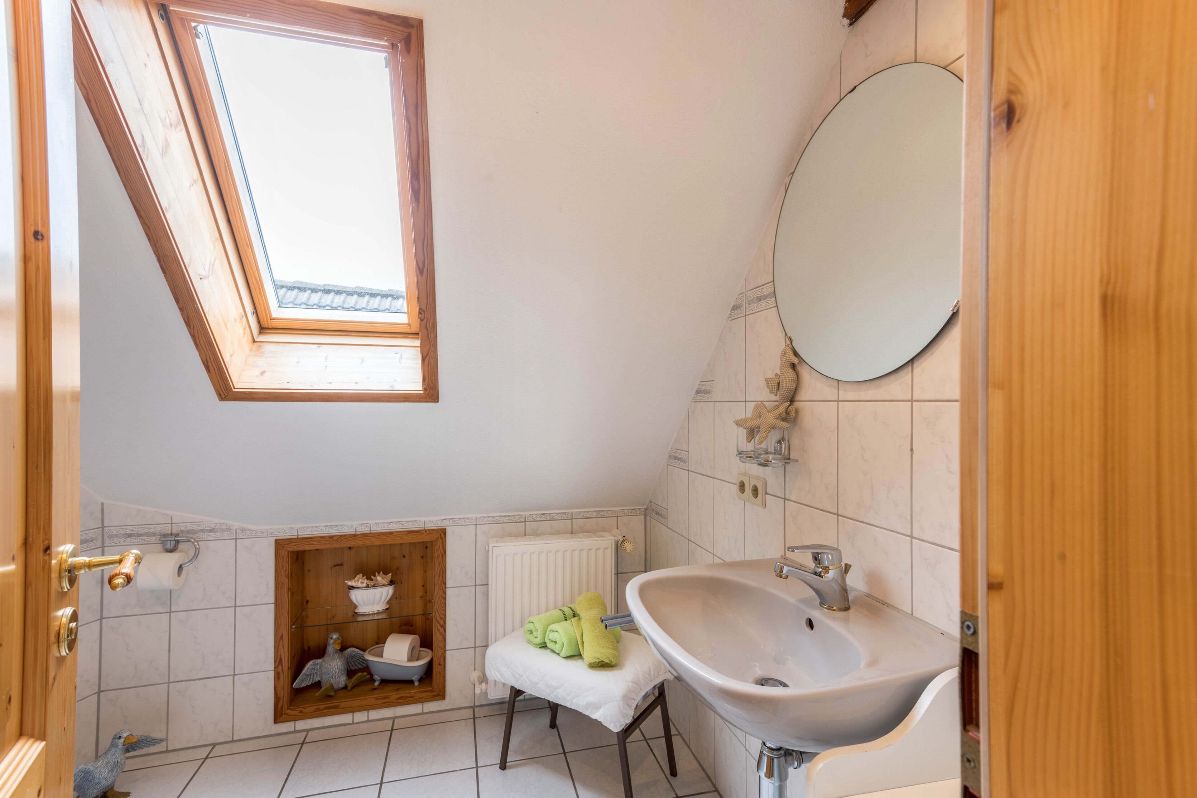 A bathroom with a skylight, a sink, a mirror, and a toilet.