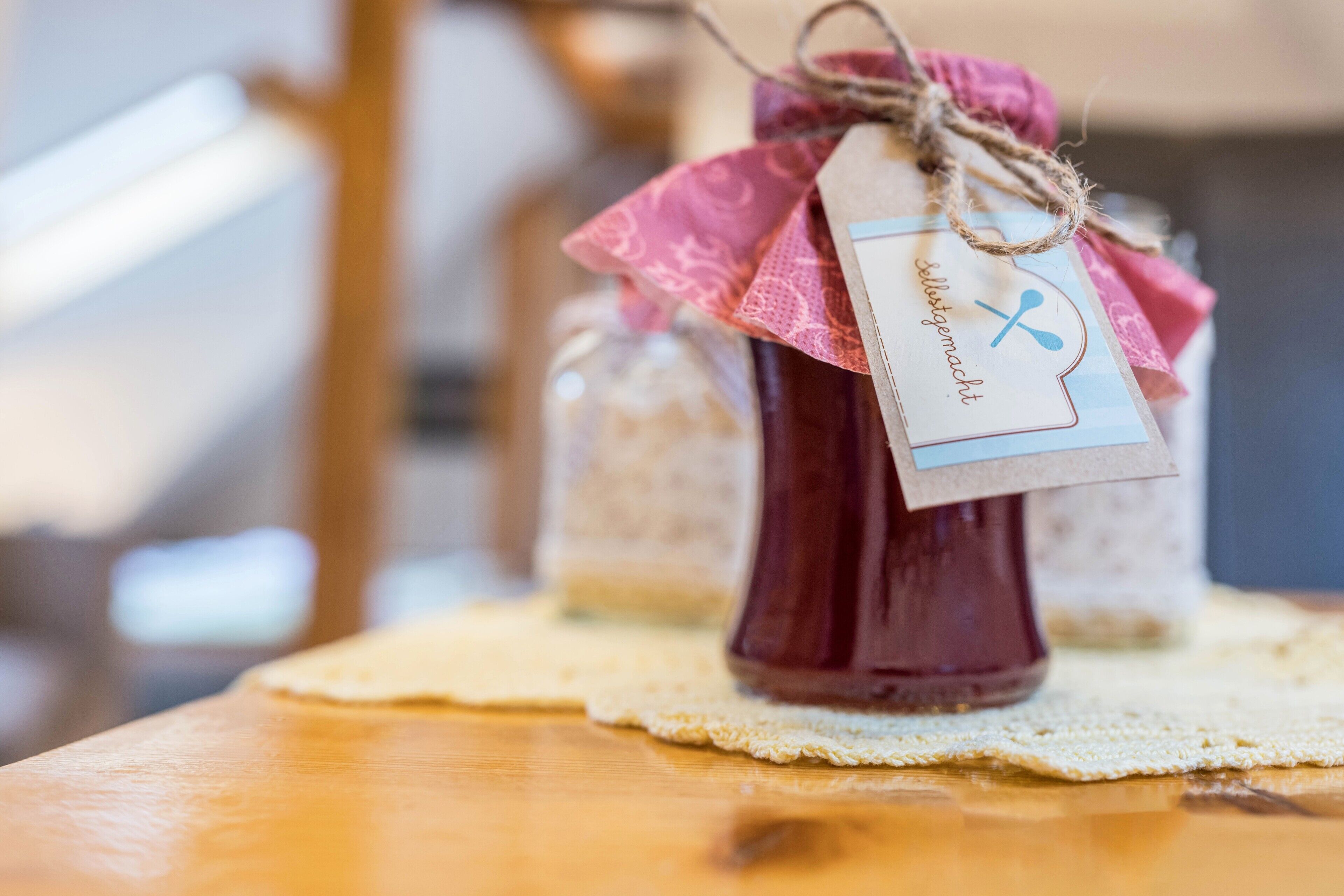 A bottle of red liquid with a tag, placed on a table with a lace doily.