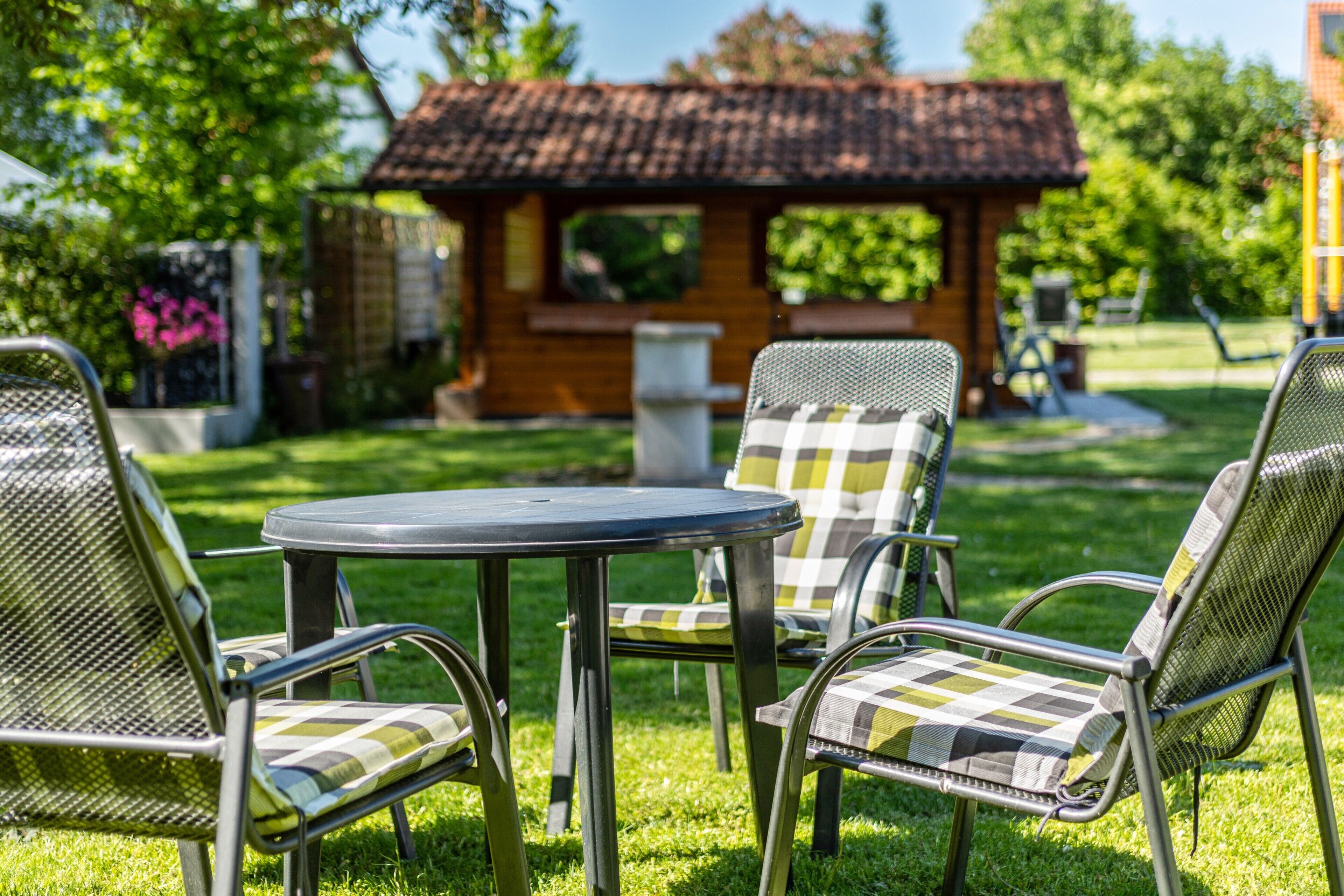 A patio with a round table and four chairs with checkered cushions.