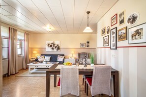 A dining area with a table set for four, a sofa, and a wall adorned with framed pictures.