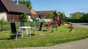 Un parque infantil con columpios y toboganes, una mesa con sillas y un área amurallada.