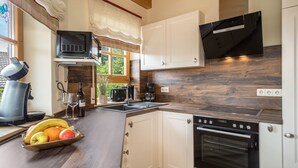 A kitchen with white cabinets, a black oven, a microwave, and a fruit bowl on the counter.
