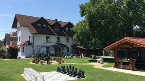 A chessboard set on a lawn with a building in the background.