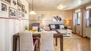 Un comedor con una mesa de madera, sillas de mimbre y un sofá al fondo.