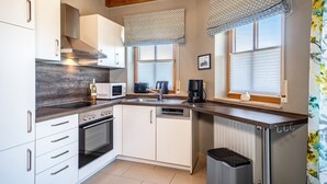 Una cocina moderna con armarios blancos, electrodomésticos de acero inoxidable y techo de madera.