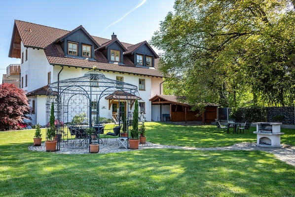A house with a conservatory, a patio with chairs, and a stone fireplace.