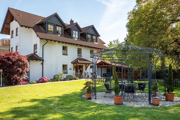 A two-story house with a garden and a metal pergola.