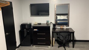 A hotel room with a desk, a chair, a television, a bed with a headboard, and a door. - Motel 6 Ponca City, OK (Ponca City)