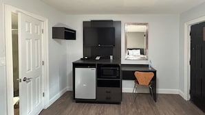 A compact room with a kitchenette, a small desk, a chair, and a mirror. - Motel 6 Ponca City, OK (Ponca City)