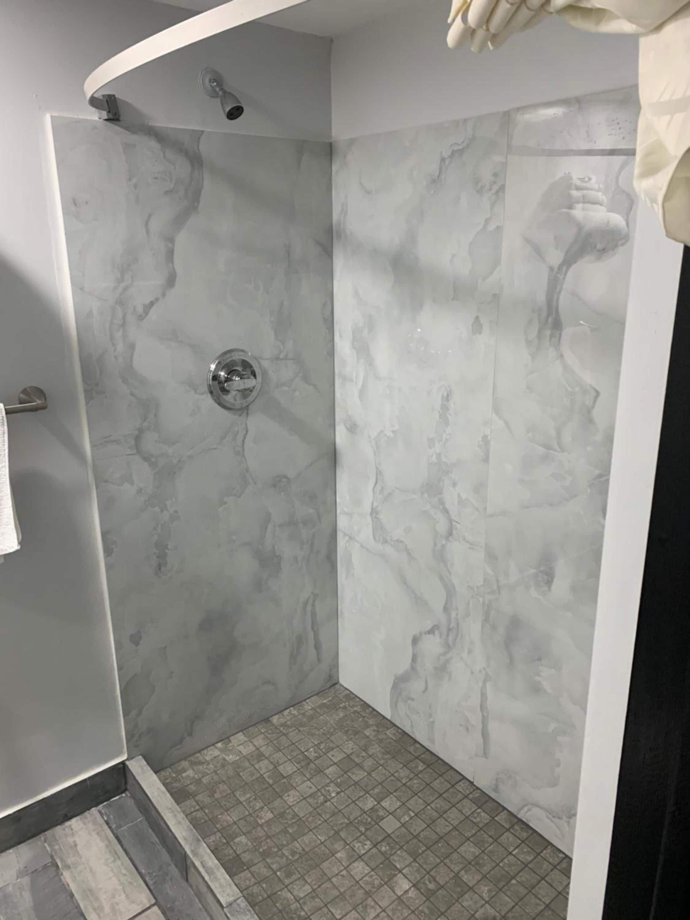 A shower with a curved ceiling and a marble wall.