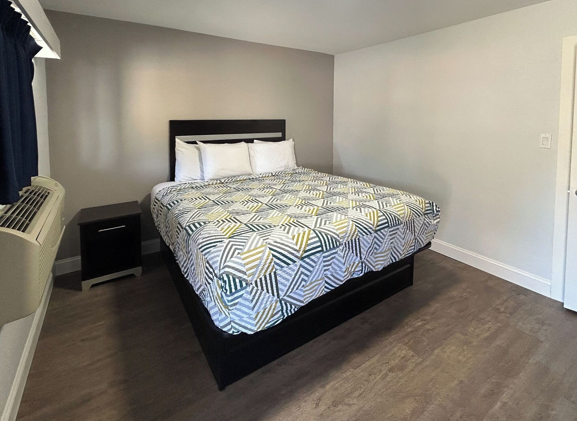 Un dormitorio con cama, mesita de noche, calefactor y puerta.