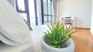 A bedroom with a bed, a potted plant, a desk, and a chair.