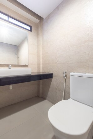 A bathroom with a white sink, a mirror, and a toilet.