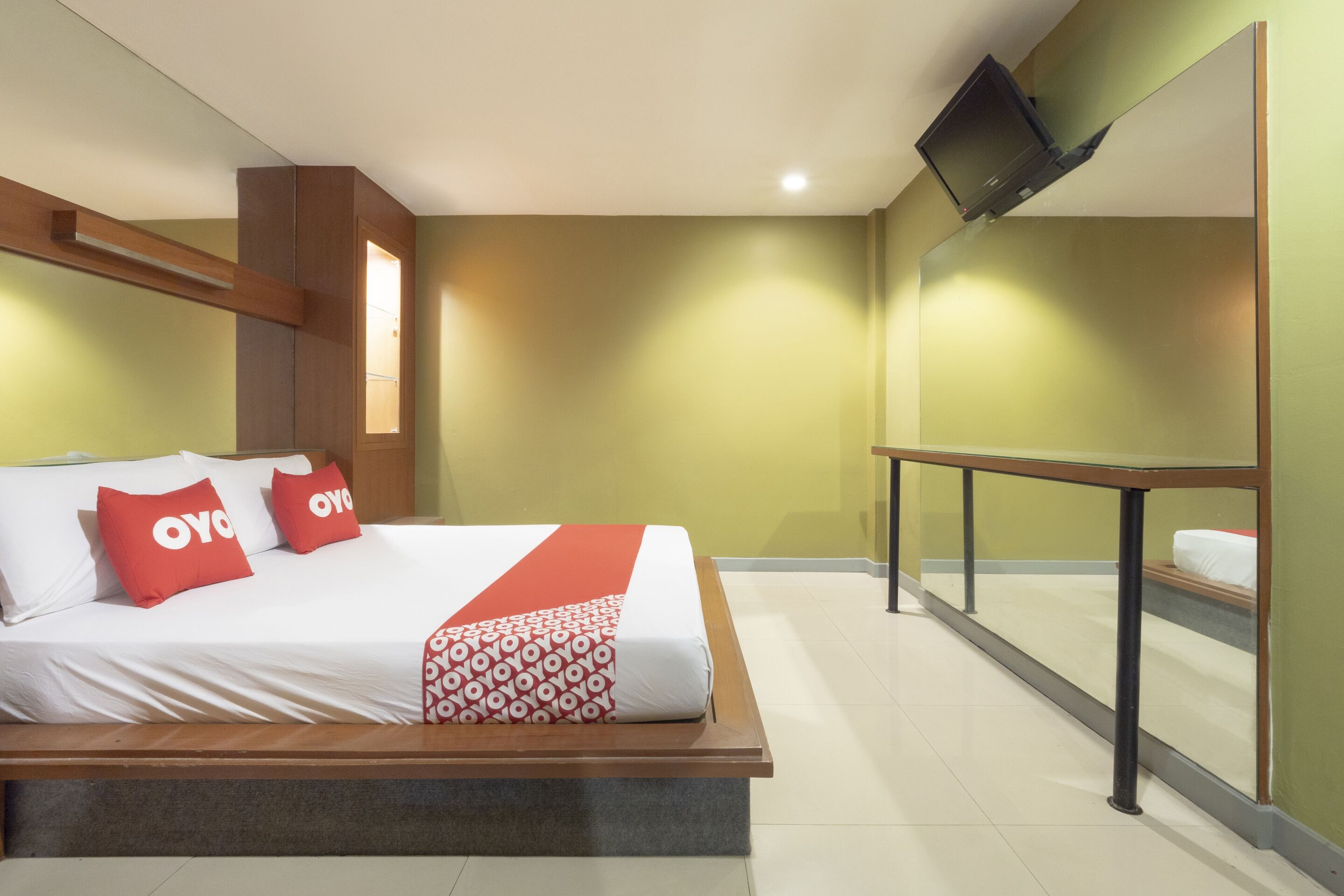 A hotel room with a bed, a TV mounted on the wall, and a window with a view.