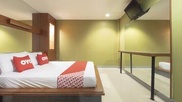 A hotel room with a bed, a TV mounted on the wall, and a window with a view.