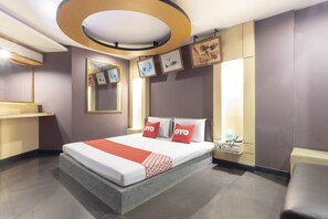 A modern hotel room with a large bed, bedside tables, a desk, and a mirror.