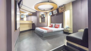 A modern hotel room with a bed, a desk, a chair, a mirror, and artwork on the walls. - OYO 75382 Chonburi Hotel (Chonburi)