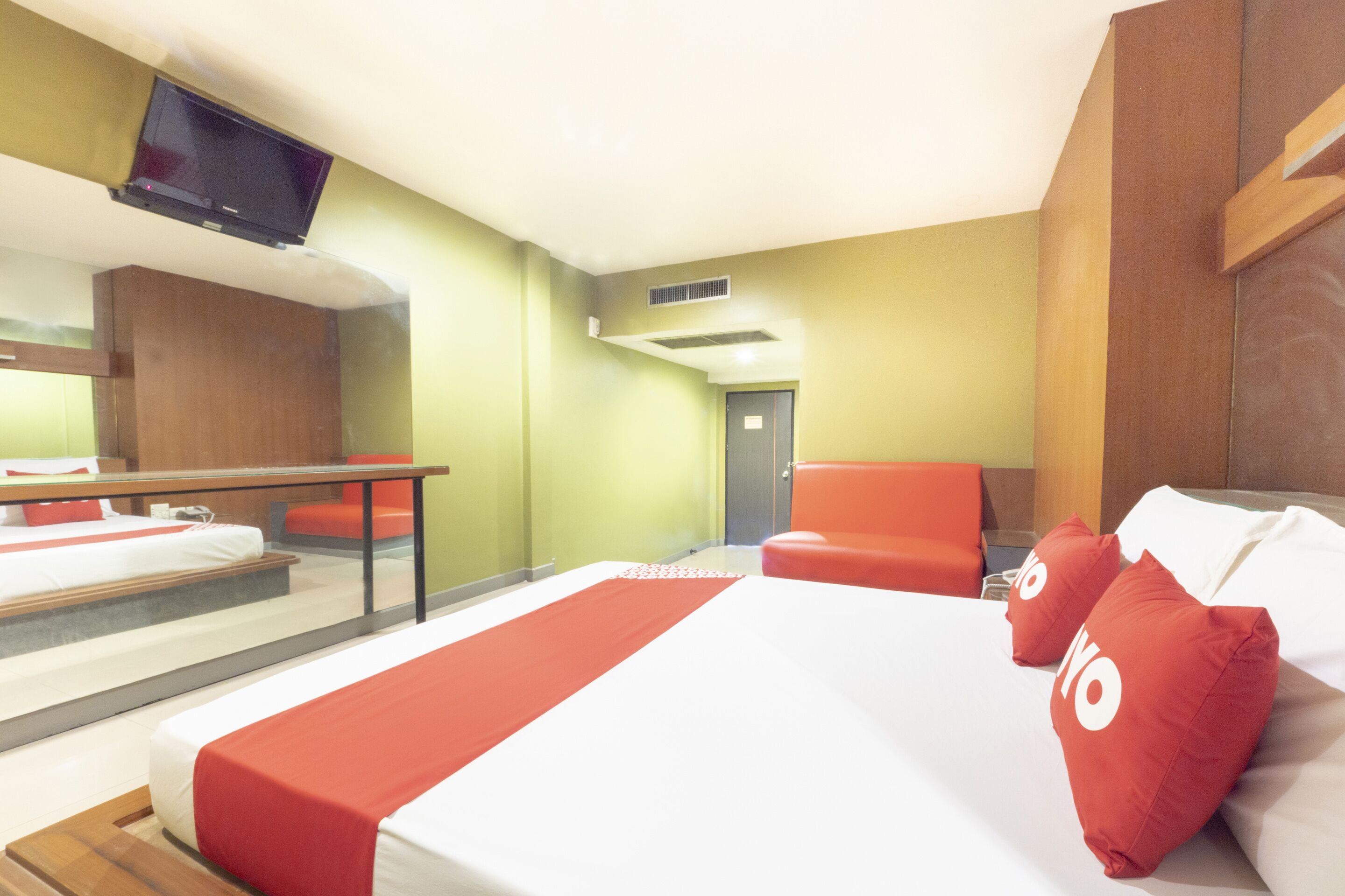 A hotel room with a bed, a desk, a chair, and a television.
