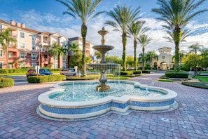 Stunning outdoor oasis with a central fountain, surrounded by lush greenery and palm trees.