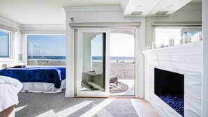 A bedroom with a bed, a fireplace, and a view of the beach through a glass door. - Entire Boardwalk Home on the Beach in Newport Beach with Beautiful Views (Newport Beach)