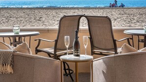 A beachside seating area with two chairs and a table, a bottle of champagne, and two glasses. - Entire Boardwalk Home on the Beach in Newport Beach with Beautiful Views (Newport Beach)