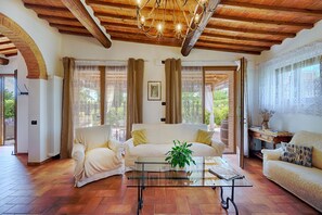 A spacious living room with a wooden ceiling, two sofas, a coffee table, and a view of greenery outside. - Villa in Siena with 4 bedrooms sleeps 8 (Siena)
