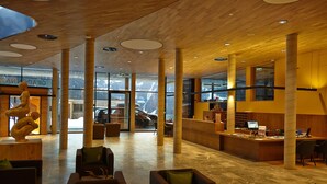 Eine geräumige Lobby mit Holzboden, großen Säulen und einer Skulptur.