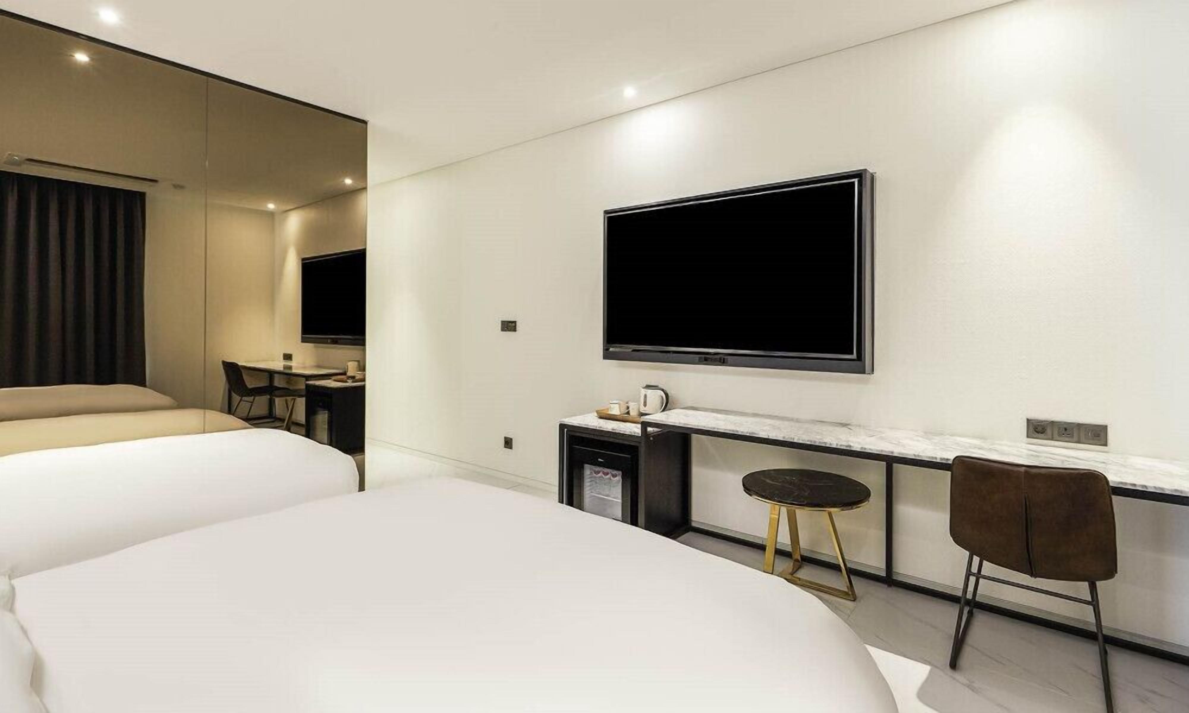 Une chambre d’hôtel moderne équipée d’un grand lit, d’un bureau avec une chaise, d’une télévision et d’une petite kitchenette.